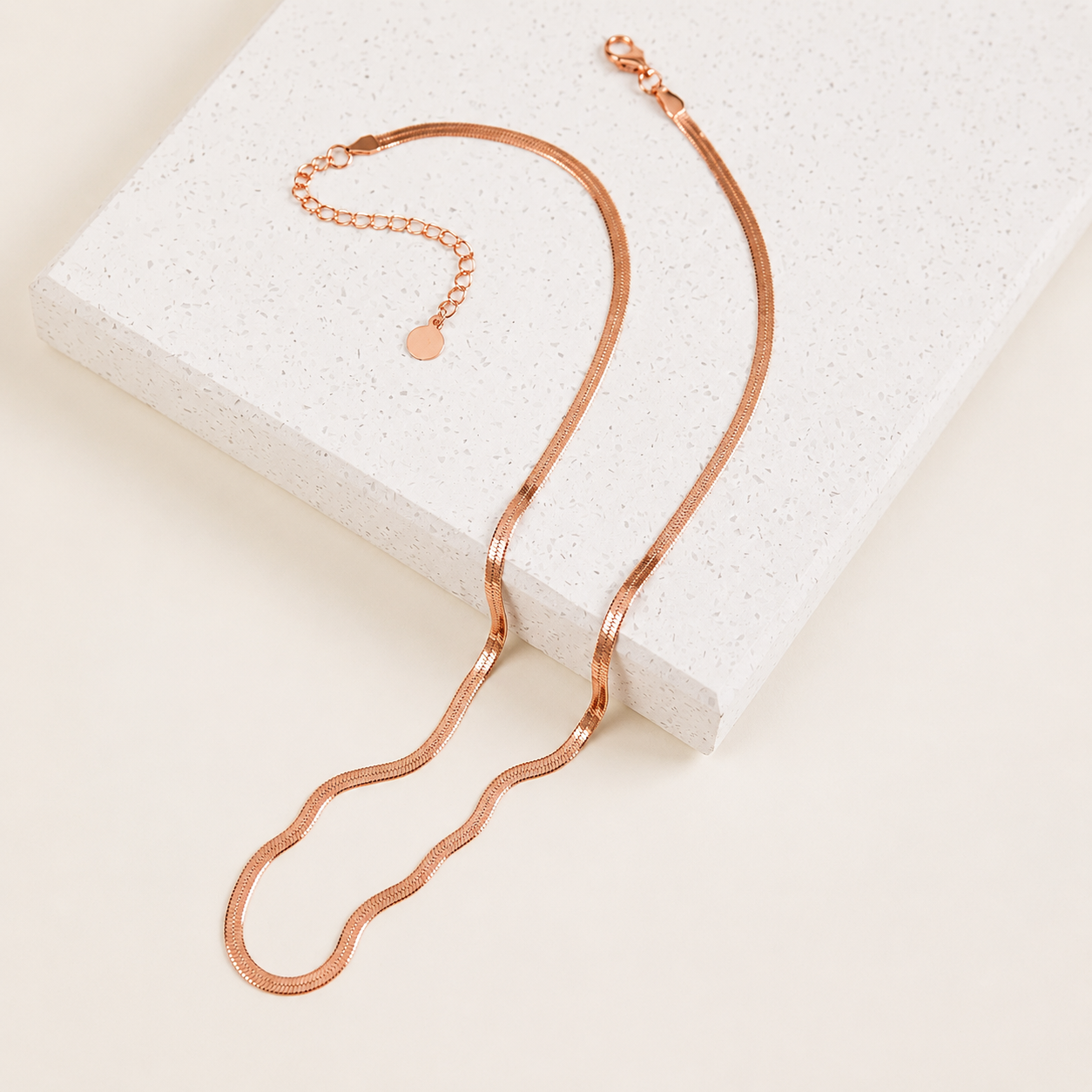 Rose gold necklace on a textured white surface